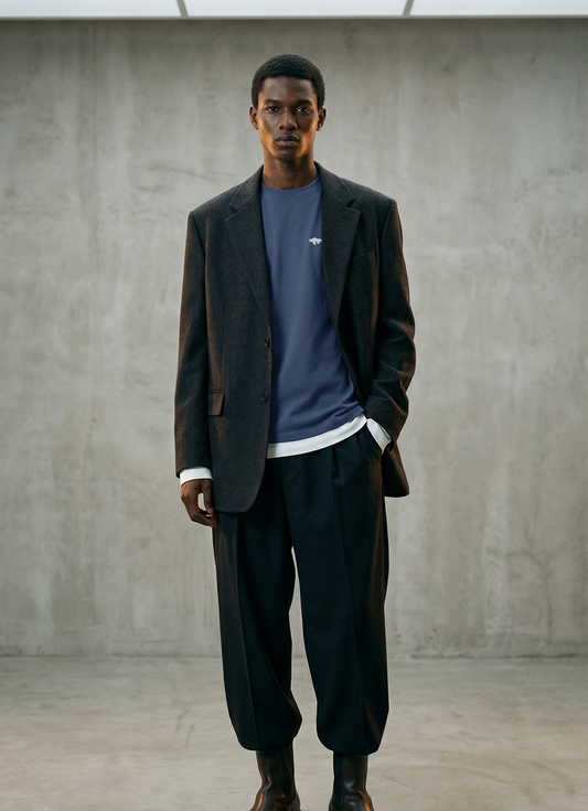 Man wearing a dark suit and blue shirt in a minimalistic room.